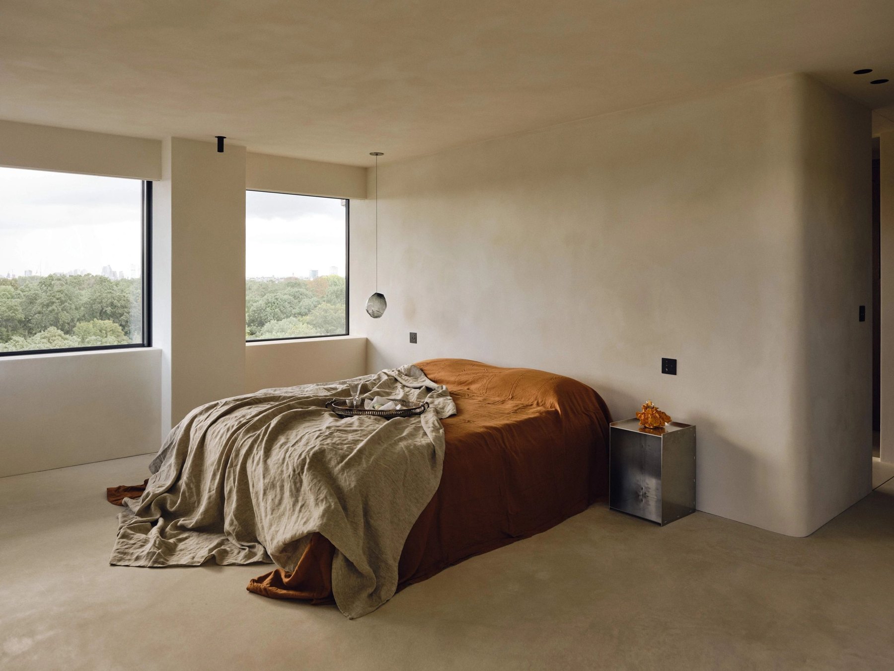 A curved timber bed in a calm bedroom overlooking the countryside