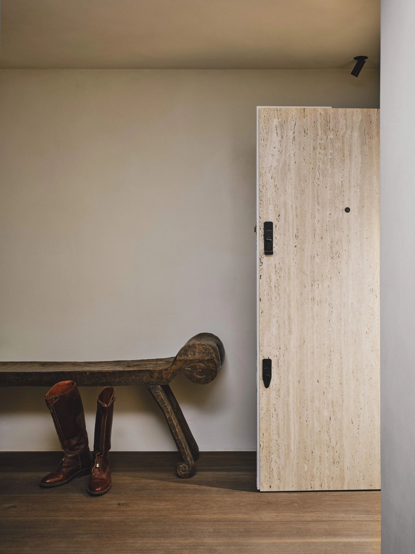 A pale timber entrance door beside a sculptural wooden bench