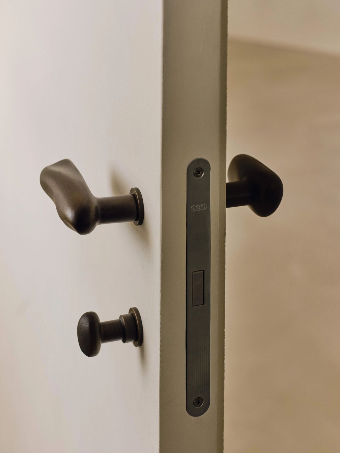 Sculptural dark metal door handles and carefully fitted ironmongery